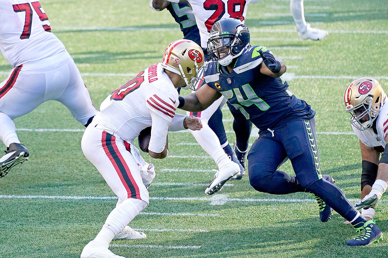 Seattle Seahawks middle linebacker Bobby Wagner, right, sacks San Francisco 49ers quarterback Jimmy Garoppolo Sunday in Seattle. (AP Photo/Elaine Thompson)