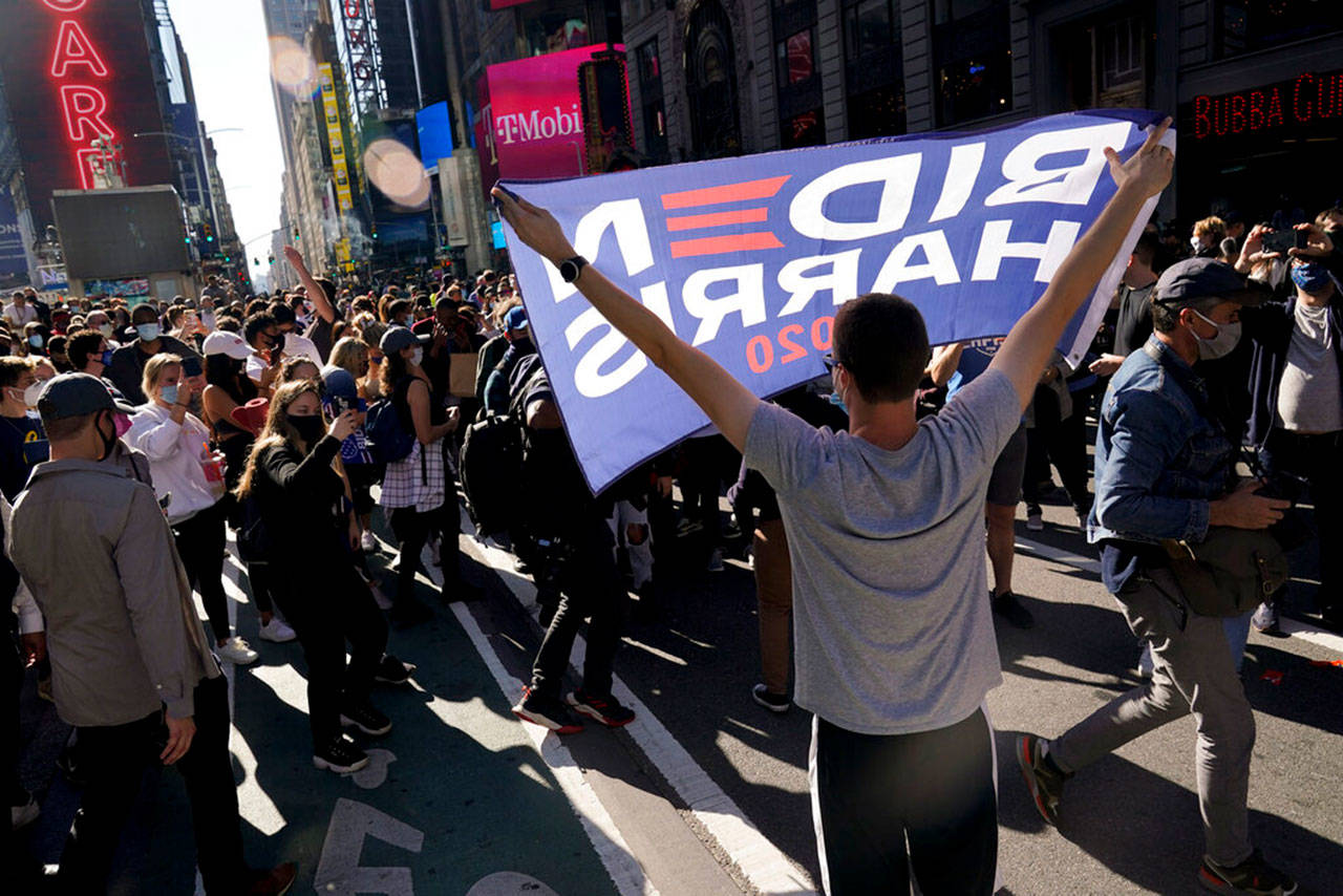 People celebrate in Times Square after former vice president and Democratic presidential candidate Joe Biden was announced as the winner over Pres. Donald Trump to become the 46th president of the United States on Saturday, Nov. 7, 2020, in New York. His victory came after more than three days of uncertainty as election officials sorted through a surge of mail-in votes that delayed the processing of some ballots. (Seth Wenig/Associated Press)