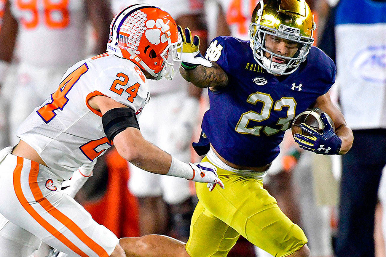 Notre Dame running back Kyren Williams (23) fends off Clemson Tigers safety Nolan Turner (24) on his way to a touchdown during the first quarter of an NCAA college football game Saturday, Nov. 7, 2020, in South Bend, Ind. (Matt Cashore/Pool Photo via AP)