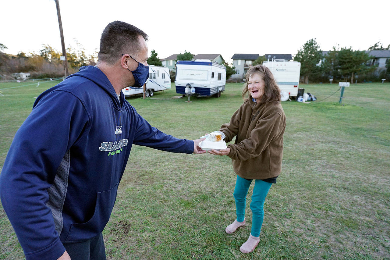 Chef Troy Murrell with Bayside Housing and Services, left, hands a hot meal to Janna Hall on Sunday at the Jefferson County Fairgrounds campground in Port Townsend. Hall, who has bipolar disorder, said she has been homeless in Port Townsend for eight years and currently lives in a tent at the fairgrounds. (Nicholas Johnson/Peninsula Daily News)