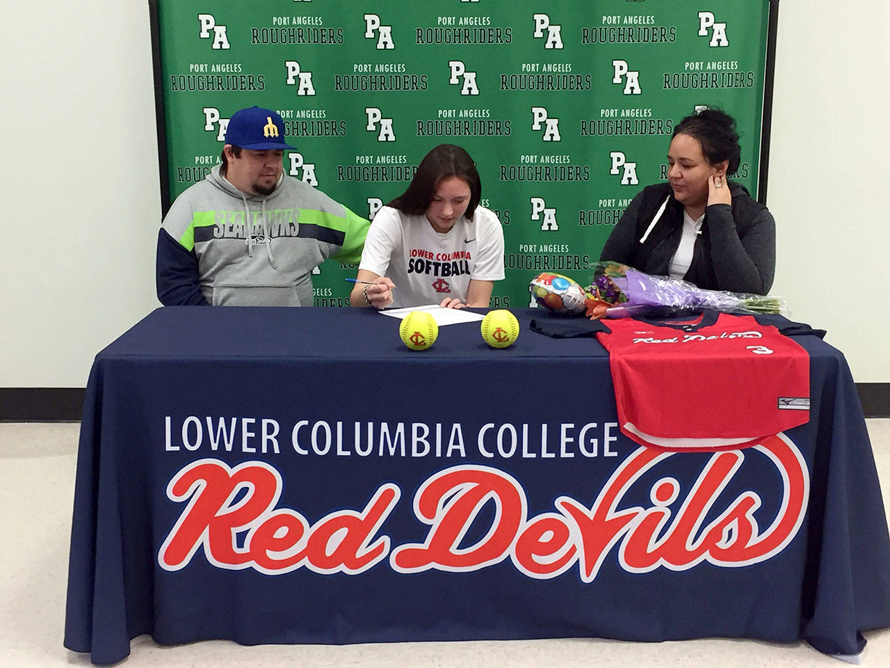 Port Angeles’ Jada Cargo signs a letter of intent to play softball for Lower Columbia Community College. Cargo is joined by her stepdad Jeremy Acosta, left, and mother, Vashti White-Acosta. (Courtesy photo)
