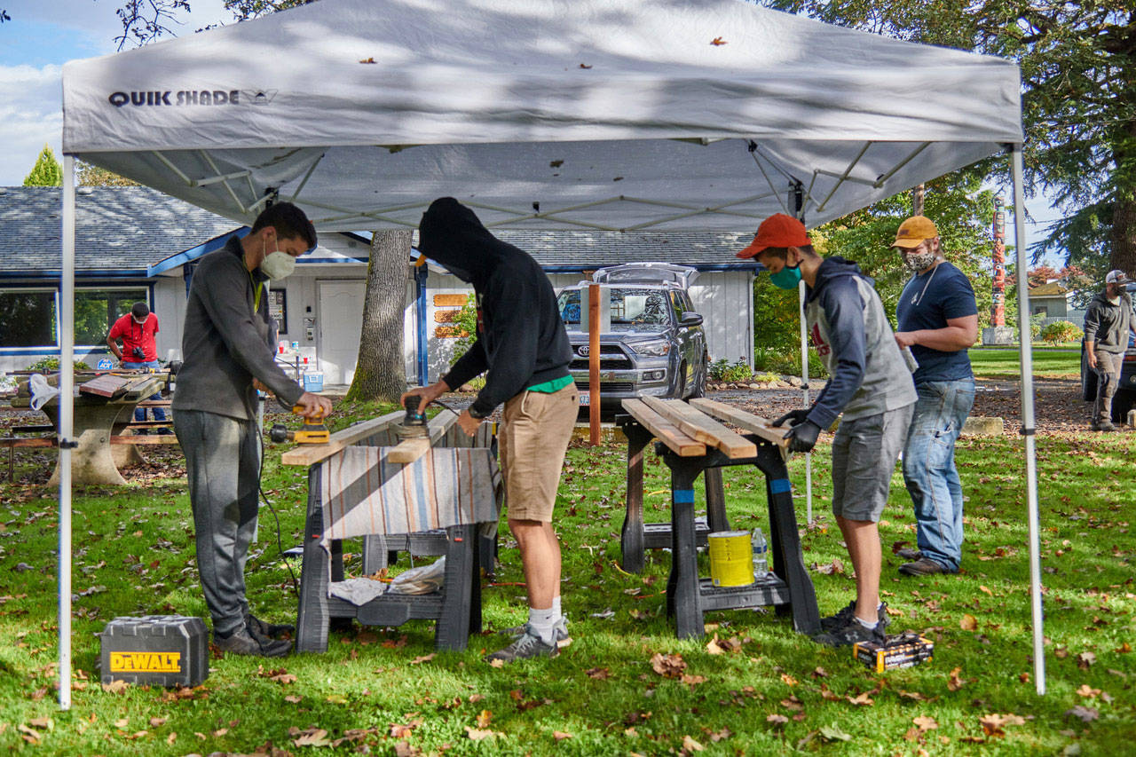 Above: Scouts and other volunteers help complete refurbishing of six picnic tables at Pioneer Memorial Park, part of Calem Ryne Klinger’s Eagle Scout project. At right: Klinger displays one of the refurbished picnic tables at Pioneer Memorial Park.Photos courtesy of Sequim Prairie Garden Club