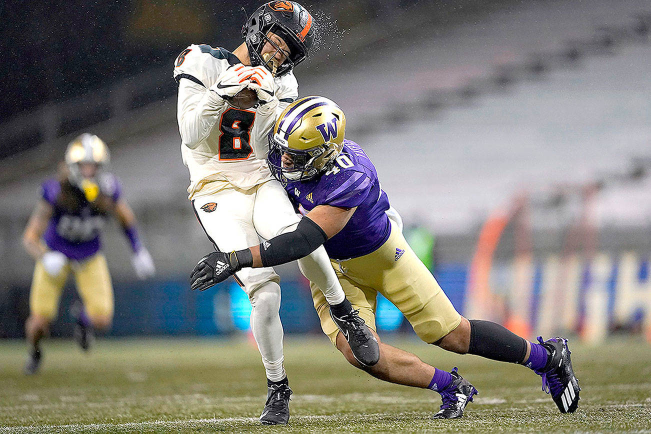 Rain water flies off the helmet of Oregon State wide receiver Trevon Bradford (8) as he is hit by Washington linebacker Alphonzo Tuputala (40) during the second half of an NCAA college football game, Saturday, Nov. 14, 2020, in Seattle. Washington won 27-21. (AP Photo/Ted S. Warren)