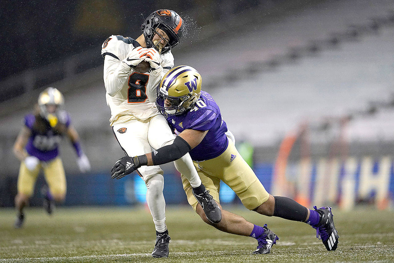 Rain water flies off the helmet of Oregon State wide receiver Trevon Bradford (8) as he is hit by Washington linebacker Alphonzo Tuputala (40) during the second half Saturday in Seattle. Washington won 27-21. (AP Photo/Ted S. Warren)