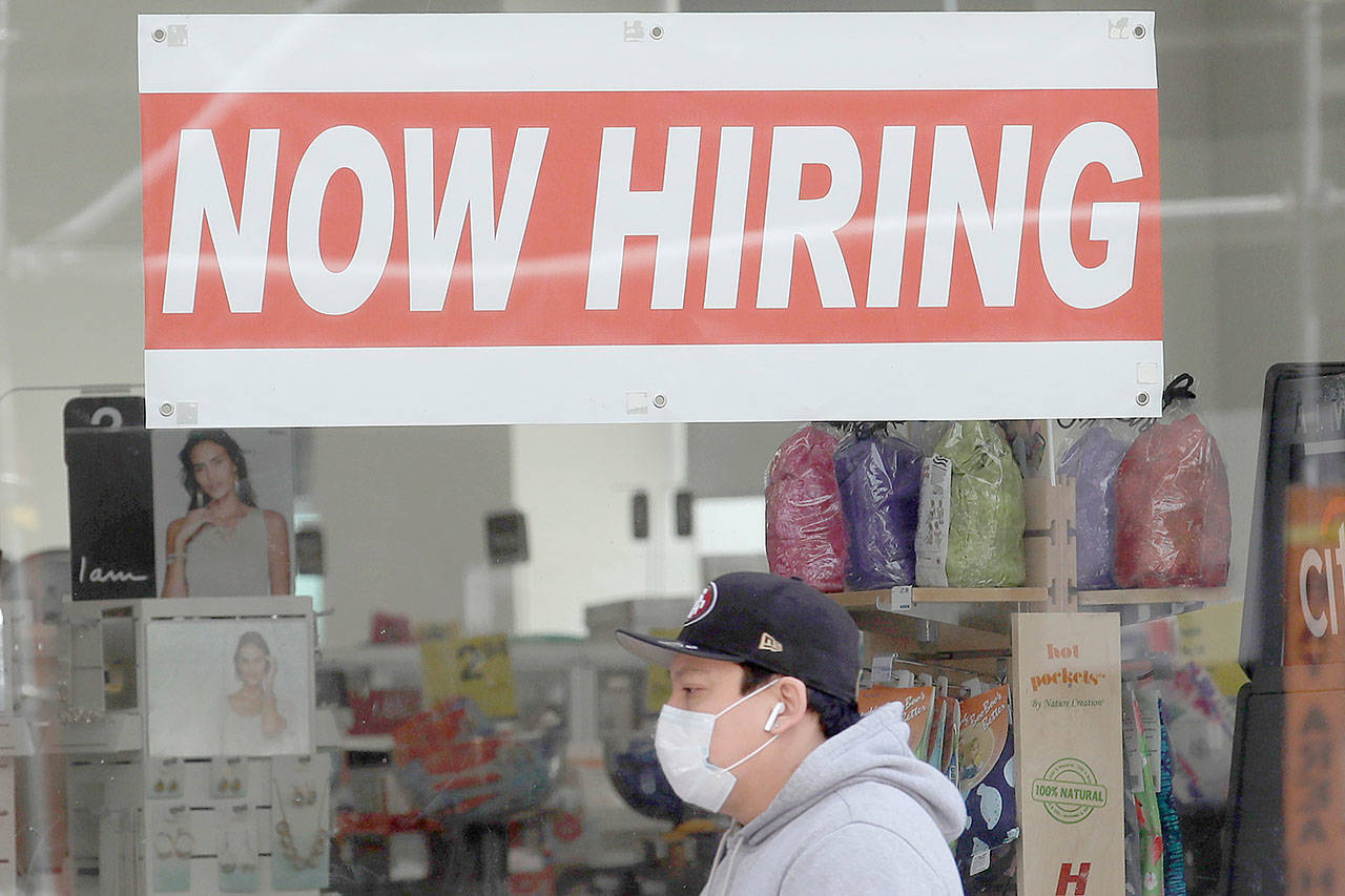 This May 7, 2020, file photo shows a man wearing a mask while walking under a Now Hiring sign at a CVS Pharmacy during the coronavirus outbreak in San Francisco. On Thursday, Nov. 12, the number of people seeking unemployment benefits fell last week to 709,000, the fourth straight drop and a sign that the job market is slowly healing. The figures coincide with a sharp resurgence in confirmed viral infections to an all-time high above 120,000 a day. (AP Photo/Jeff Chiu, File)