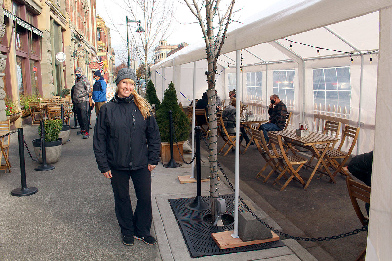 Whiskey Mill, Alchemy and Sirens owner Kris Nelson stand in front of the busy outdoor dining tent at Whiskey Mill as lunch patrons dine in the afternoon. Due to reinstated restrictions by Gov. Jay Inslee, restaurants are required to serve food either to go or outdoors. (Zach Jablonski/Peninsula Daily News)