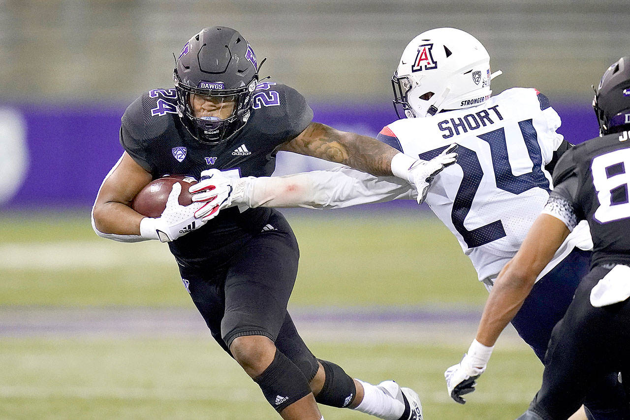 Washington’s Kamari Pleasant, left, pushes away Arizona’s Rhedi Short on Pleasant’s 21-yard touchdown run during the second half Saturday in Seattle. (AP Photo/Elaine Thompson)