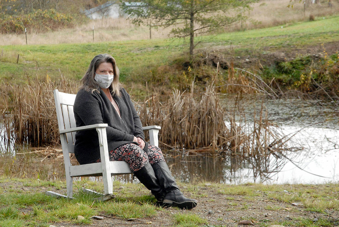 Nurse and COVID-19 survivor Laura Dotlich sits next to a small pond at her home in rural Port Angeles on Thursday. (Keith Thorpe/Peninsula Daily News)