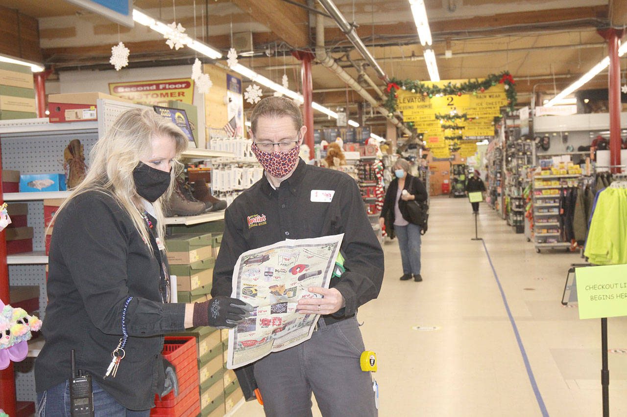 Don Droz, the current manager of Swains, confers with Penny Doane about their sales from the store’s advertising flyer. (Dave Logan / For the Peninsula Daily News)