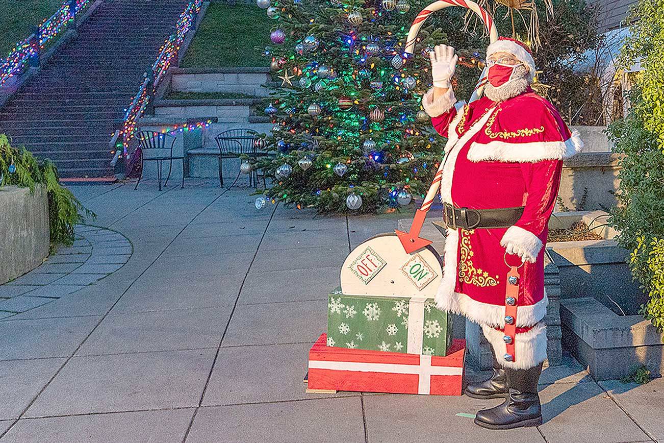 Santa Claus waves to a few spectators after pulling the lever to light the community Christmas tree Saturday at Haller Fountain in Port Townsend. (Steve Mullensky/For Peninsula Daily News)