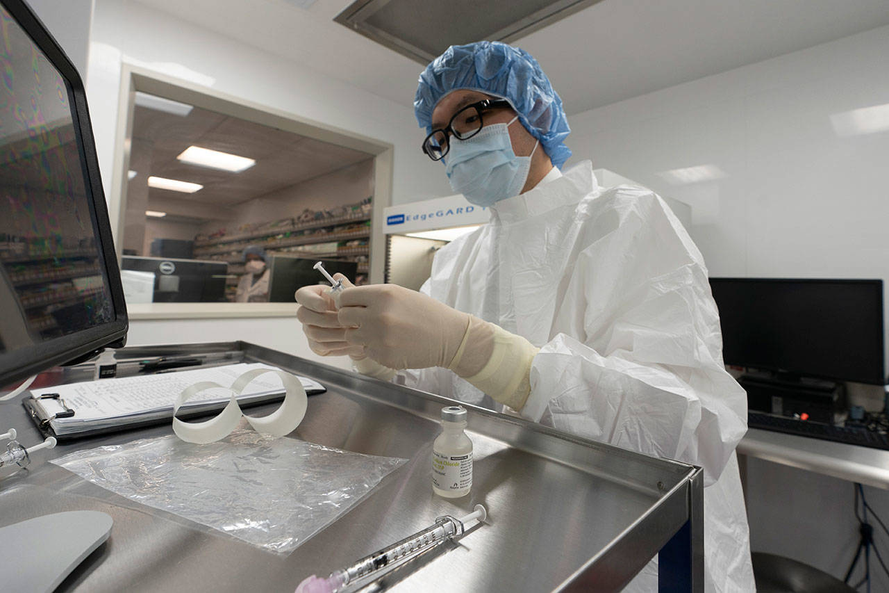 A pharmacist labels syringes in a clean room where doses of COVID-19 vaccines will be handled Wednesday, Dec. 9, 2020, at Mount Sinai Queens hospital in New York. The hospital expects to receive doses once a vaccine gets the emergency green light by U.S. regulators (Mark Lennihan/Associated Press)