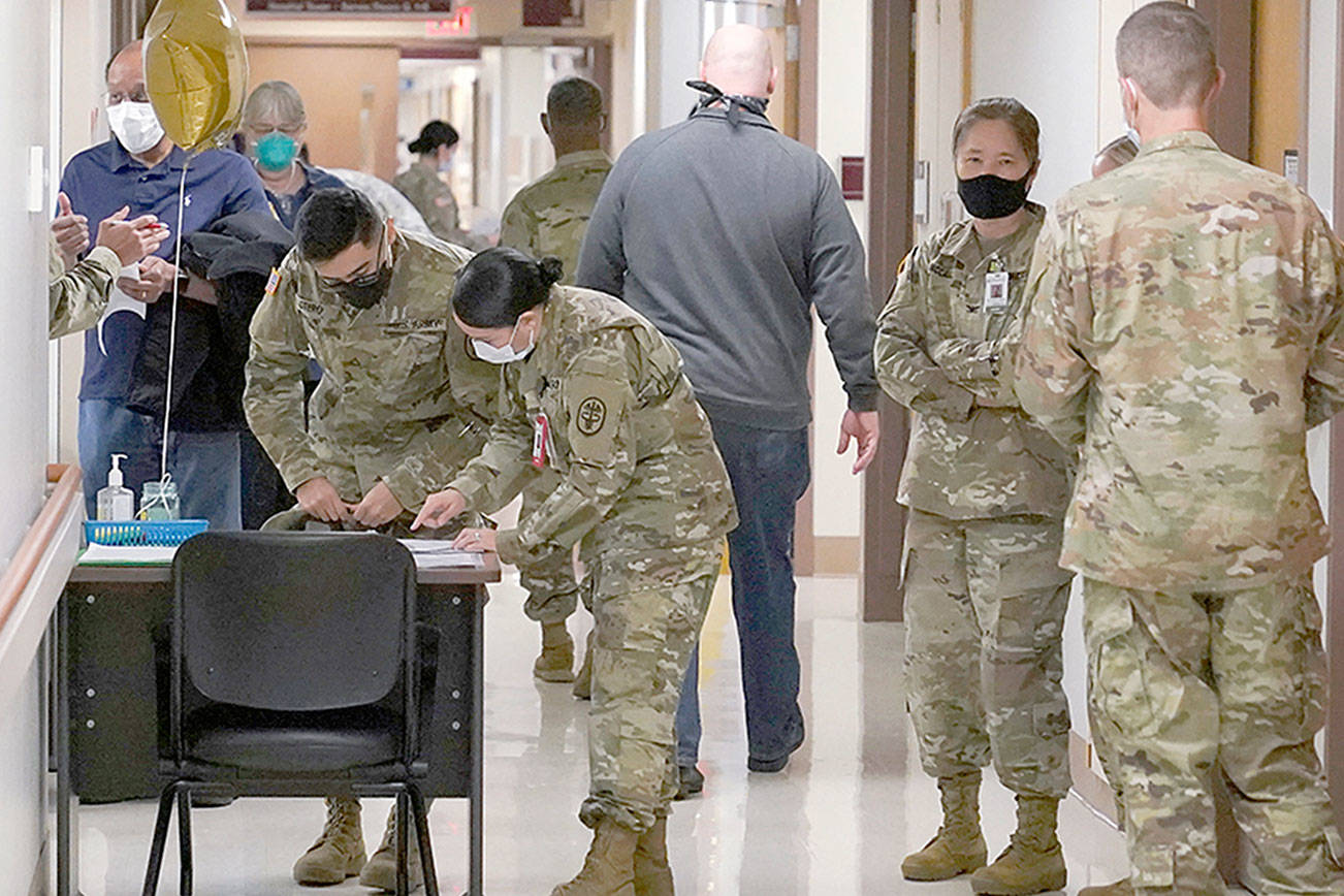 Health care workers staff a check in station for people receiving the first doses of the Pfizer vaccine for COVID-19, Wednesday, Dec. 16, 2020, at Madigan Army Medical Center at Joint Base Lewis-McChord in Washington state, south of Seattle. Vaccinations are scheduled to continue in the coming weeks for front-line medical workers and and others in high-priority positions at the base. (AP Photo/Ted S. Warren)