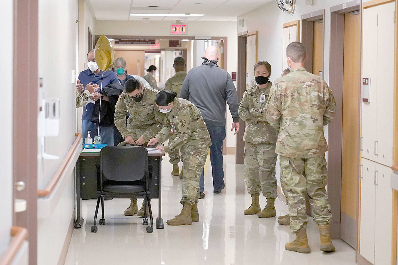 Health care workers staff a check in station for people receiving the first doses of the Pfizer vaccine for COVID-19 on Wednesday, Dec. 16, 2020, at Madigan Army Medical Center at Joint Base Lewis-McChord in Washington state, south of Seattle. Vaccinations are scheduled to continue in the coming weeks for front-line medical workers and and others in high-priority positions at the base. (Ted S. Warren/Associated Press)