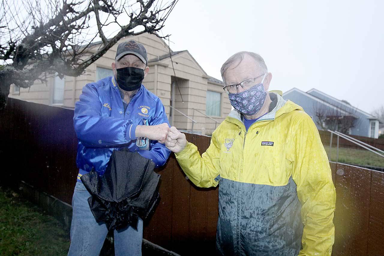 Lloyd Bedinger, left, and Bruce Skinner, the executive director of the Olympic Medical Center Foundation, share a fist bump in front of the Georgiana Street home Bedinger donated to the foundation in his mother’s name. Helen Rice, a former OMC employee, lived in the house for more than 60 years before she died in March at age 106. (Dave Logan/for Peninsula Daily News)