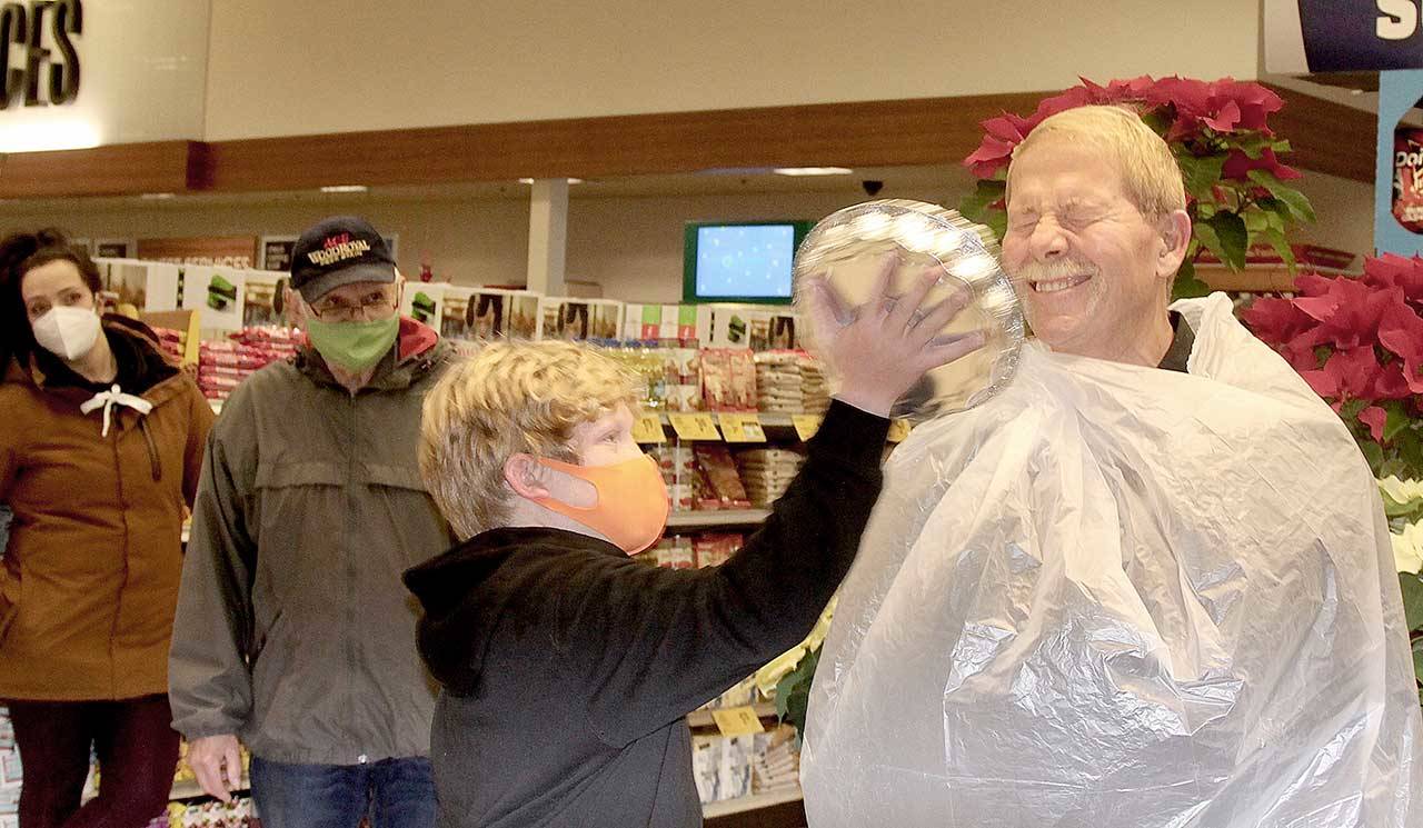 Sequim Mayor William Armacost takes a whipped cream pie in the face from Ben Clemens, 10, the son of Port Angeles Mayor Kate Dexter, at the Port Angeles Safeway store on Lincoln Street. This event is the culmination of a challenge between Safeway stores in the two towns to see which could raise more donations for local food banks. (Dave Logan/for Peninsula Daily News)