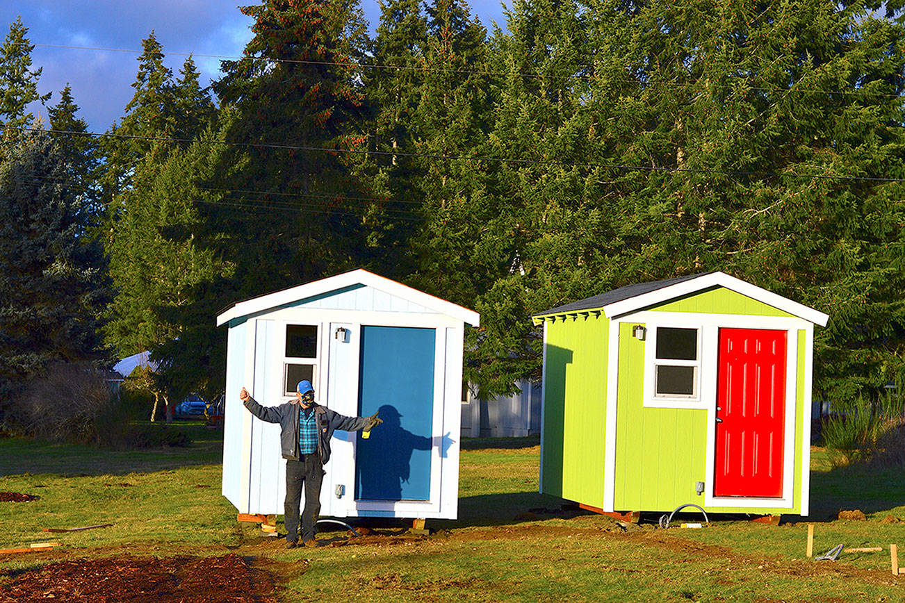 Volunteer builder Randy Welle prepares to welcome people to the Bayside Housing village in Port Hadlock. The sky-blue shelter is named Beth's House in honor of cofounder Peter Bonyun's late wife Beth Lorber.  Diane Urbani de la Paz/Peninsula Daily News
