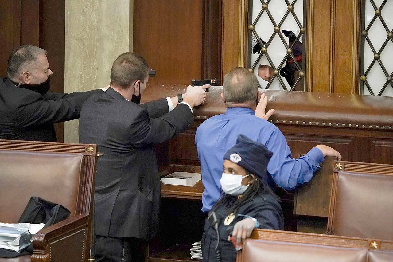 Police with guns drawn watch as protesters try to break into the House Chamber at the U.S. Capitol on Wednesday in Washington, D.C. (J. Scott Applewhite/The Associated Press)