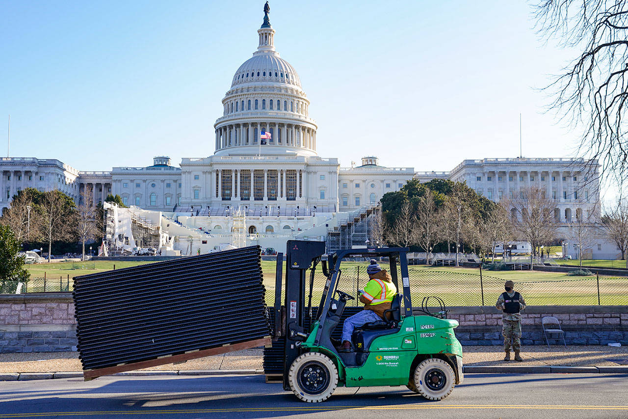DC National Guard stands outside a mostly quiet Capitol, Thursday morning in Washington, as workers place security fencing in place. The House and Senate certified the Democrat’s electoral college win early Thursday after a violent throng of pro-Trump rioters spent hours Wednesday running rampant through the Capitol. A woman was fatally shot, windows were bashed and the mob forced shaken lawmakers and aides to flee the building, shielded by Capitol Police. (AP Photo/John Minchillo)