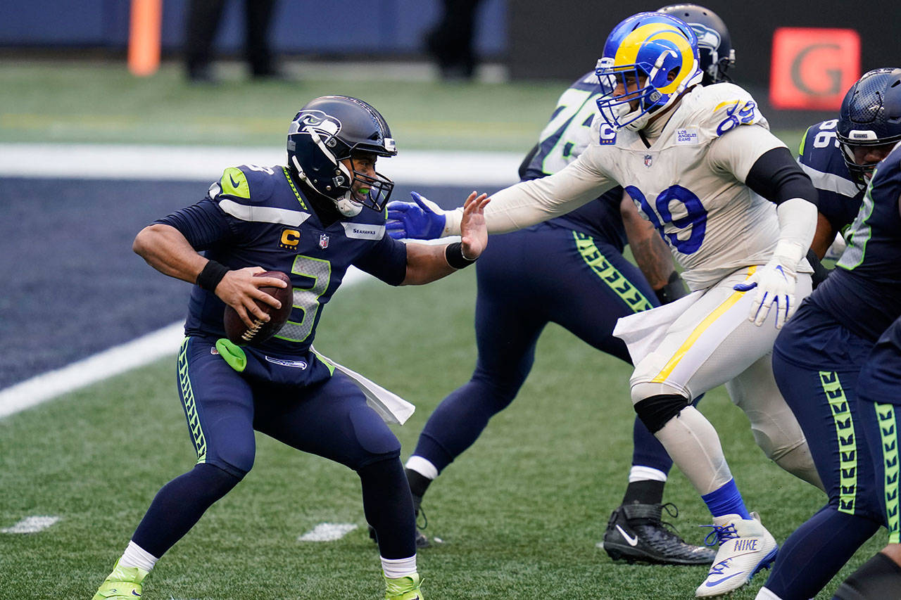 Seattle Seahawks quarterback Russell Wilson (3) tries to fend off a sack by Los Angeles Rams defensive lineman Aaron Donald (99) during the second half of an NFL football game Dec. 27 in Seattle. (Elaine Thompson/The Associated Press)