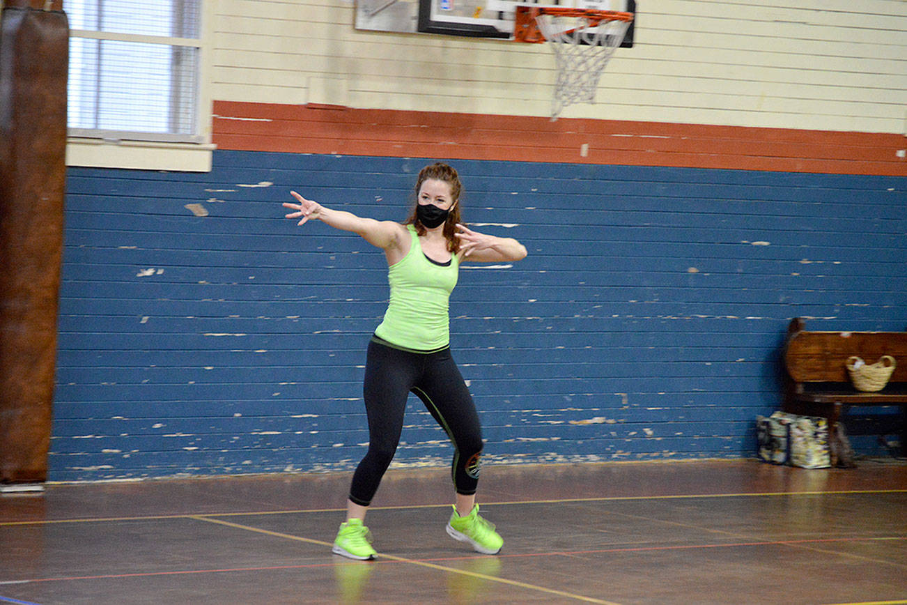 Independent Zumba instructor Bailey Burkhartsmeier teaches a spread-out, masked class for a handful of students at the Port Townsend Community Center on Tuesday morning. Statewide guidelines allowing in-person exercise — with restrictions — are inspiring fitness enthusiasts to come back to gyms and yoga studios this week. (Diane Urbani de la Paz/Peninsula Daily News)