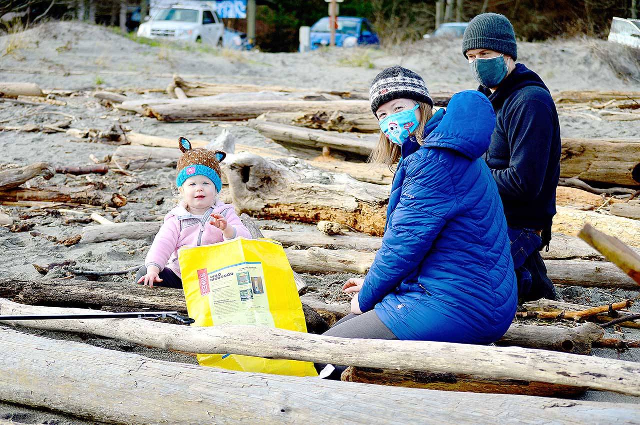 Eowyn Reardon, 22 months, assisted parents Benjamin Reardon and Amy Johnson of Port Townsend at the Martin Luther King Jr. Day beach cleanup on Monday. Scores of people took to the shores at Fort Worden State Park for the event hosted by the Port Townsend Marine Science Center. (Diane Urbani de la Paz/Peninsula Daily News)