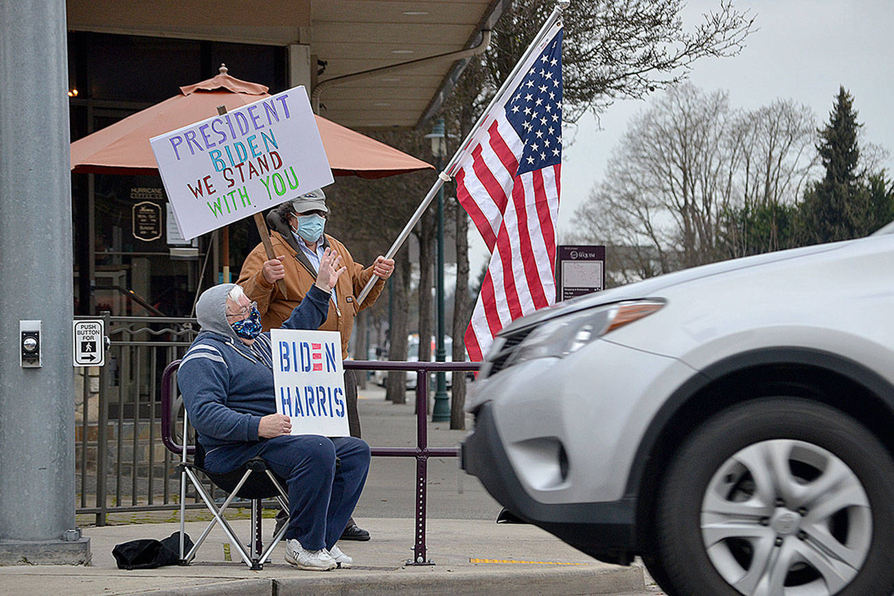 Steve Downer and Brian Grad, both of Sequim, wave to drivers on Jan. 20 as they celebrate the inauguration of President Joe Biden and Vice-President Kamala Harris. “I’m relieved,” Downer said of the inauguration. He hopes their first steps will be to address COVID-19, the economy and environment.
Matthew Nash/ Olympic Peninsula News Group