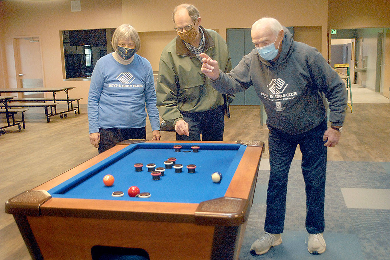 Keith Thorpe/Peninsula Daily News
Boys & Girls Clubs of the Olympic Peninsula board member Norma Turner, left, and her husband, long time volunteer Gene Turner, right, play with a bumper pool table with construction facilitator Steve Zenovic in the game room of the new Port Angeles Unit's building, which has been named the Turner Clubhouse in honor of the Turner's contributions to the club's success.