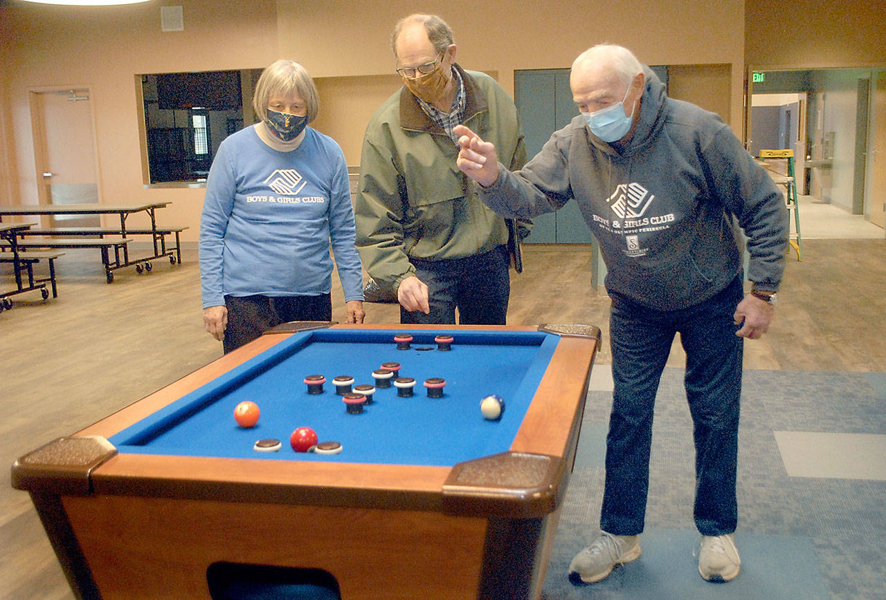 Boys & Girls Clubs of the Olympic Peninsula board member Norma Turner, left, and her husband, long time volunteer Gene Turner, right, play with a bumper pool table with construction facilitator Steve Zenovic in the game room of the new Port Angeles Unit’s building, which has been named the Turner Clubhouse in honor of the Turner’s contributions to the club’s success. (Keith Thorpe/Peninsula Daily News)