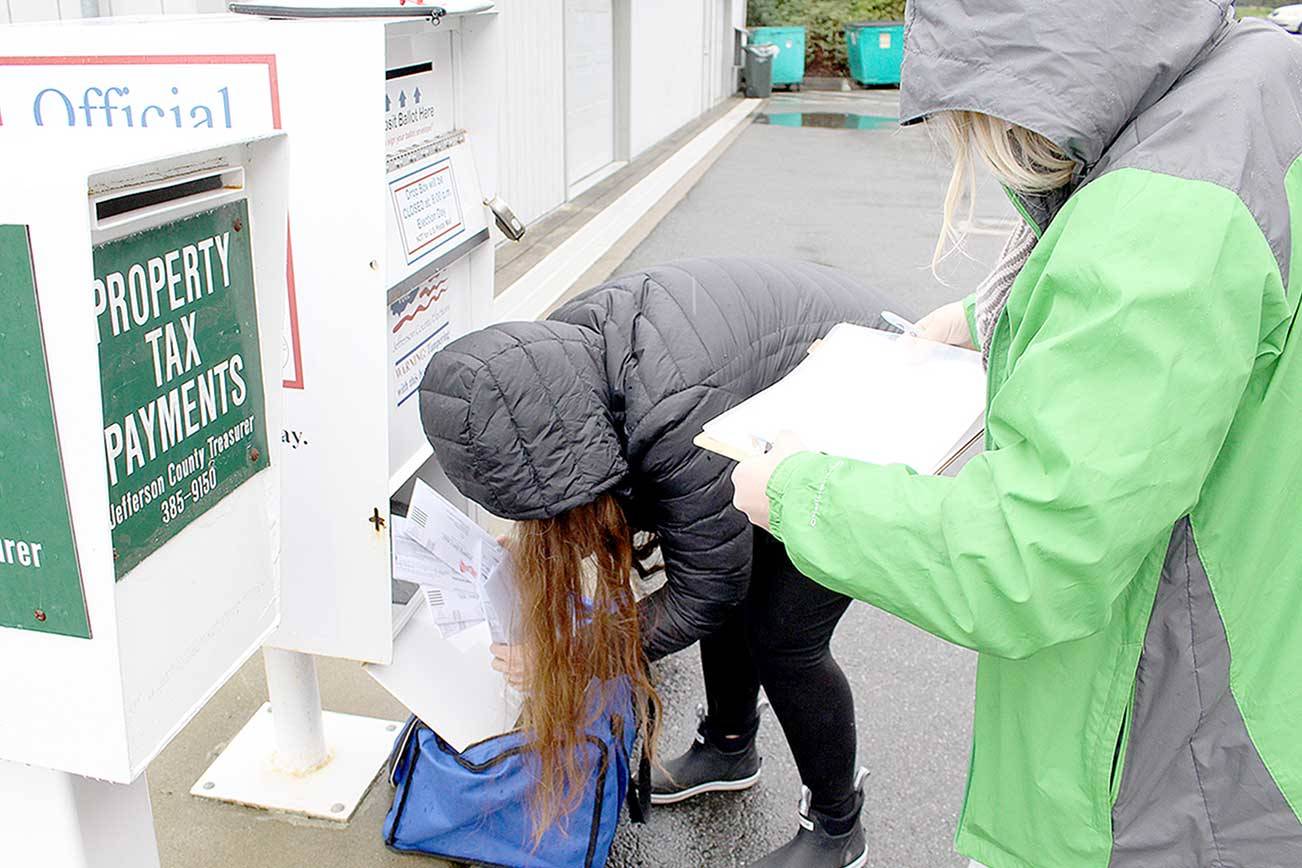 Jefferson County Voter Registration Coordinator Sandi Eldridge, left, and Election Coordinator Quinn Grewell collect ballots in the rain Thursday morning from the dropbox behind the Jefferson County Courthouse. Residents voting in the Feb. 9 special election have until 8 p.m. Tuesday to return their ballot to an official election dropbox. (Zach Jablonski/Peninsula Daily News)