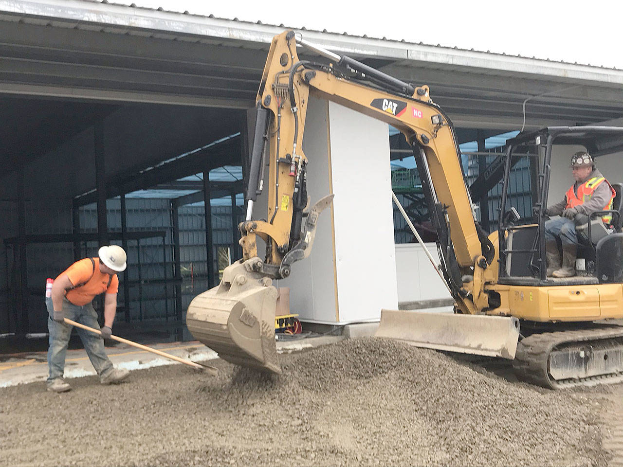 Chimacum resident Wally Huntingford, an equipment operator with ICI of Sequim, and laborer Quenton Wolfer of Port Angeles prepared the Grocery Outlet site Friday for a new sidewalk. (Paul Gottlieb/Peninsula Daily News)
