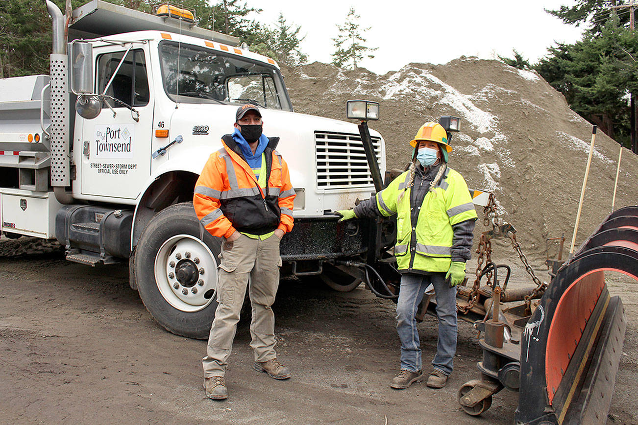 Port Townsend Public Works Crew Chief Chris MacDonald, left, stands with Tracy Benson, equipment operator, on Wednesday in front of one of the snow plows they and their other team members will use to keep roads clear in Port Townsend. Snow is forecast in the next few days. (Zach Jablonski/Peninsula Daily News)