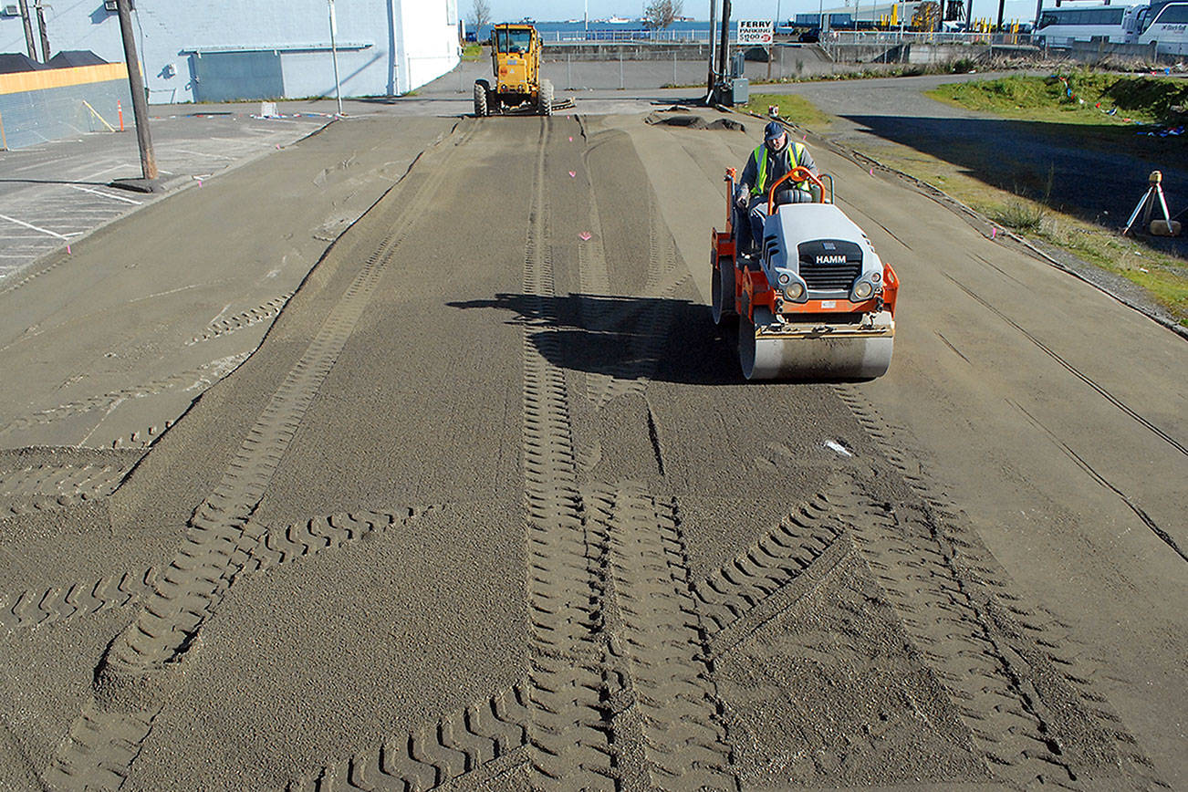 Keith Thorpe/Peninsula Daily News
Richard Brandt of Lakeside Industries uses a steam roller on a layer of sand on Thursday to create a level surface that will become the base for a temporary ice skating rink in a city parking lot along Front Street in downtown Port Angeles. The rink wil be the centerpiece for the annual Port Angeles Ice Village, which would normally be held in the winter months but was moved to spring because of restrictions imposed by COVID-19. Skating is scheduled to begin on March 19 and run through April 18.