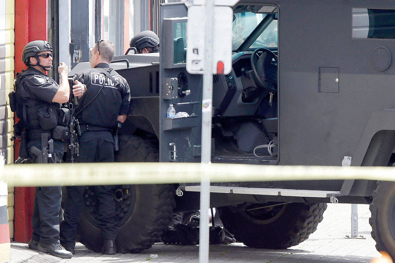 In this June 6, 2014, file photo, Seattle Police SWAT team officers stand behind an armored vehicle in Seattle’s Capitol Hill neighborhood. Lawmakers are on the cusp of overhauling policing and police accountability in Washington state, acting with unusual urgency to curb bad behavior by officers following last year’s turbulent protests for racial justice. (Ted S. Warren/The Associated Press, file)