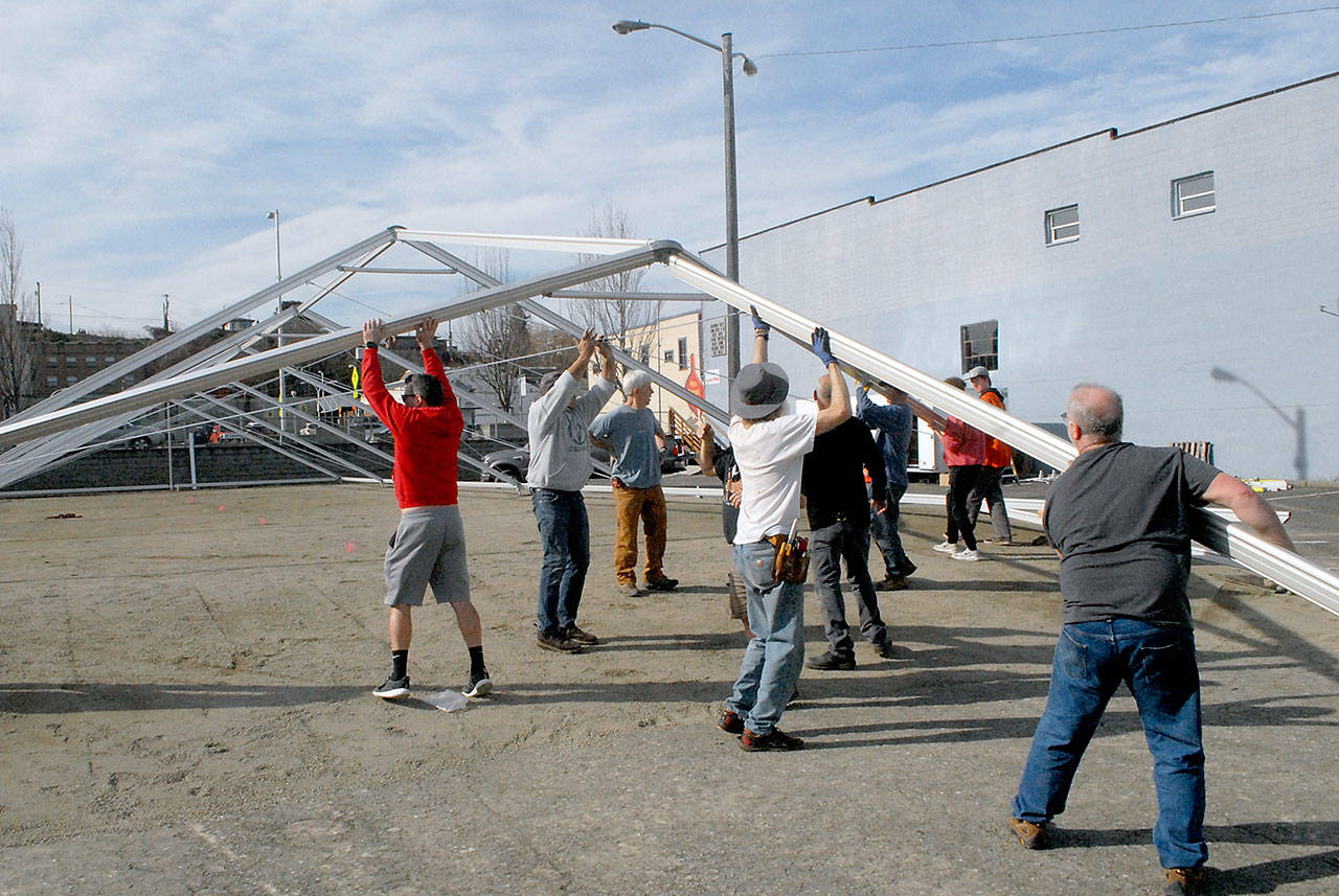 Volunteers work on Saturday to erect an events tent that will cover a temporary ice skating rink, the centerpiece of the Port Angeles Ice Village. Normally held during the winter months but delayed until spring due to COVID-19 restrictions, this year’s skating will open on Friday and run through April 18 in a city-owned parking lot in the 100 block of West Front Street in downtown Port Angles. Skating will be open daily from 9 a.m. to 9 p.m. (Keith Thorpe/Peninsula Daily News)
