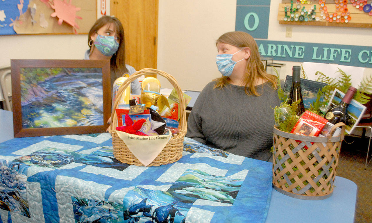 <strong>Keith Thorpe</strong>/Peninsula Daily News
Feiro Marine Life Center Development Director Linty Hopie, left, and Executive Director Melissa Williams sit with some of the auction items to be sold at the center’s Making Waves 2021: Resilience online fundraising event.