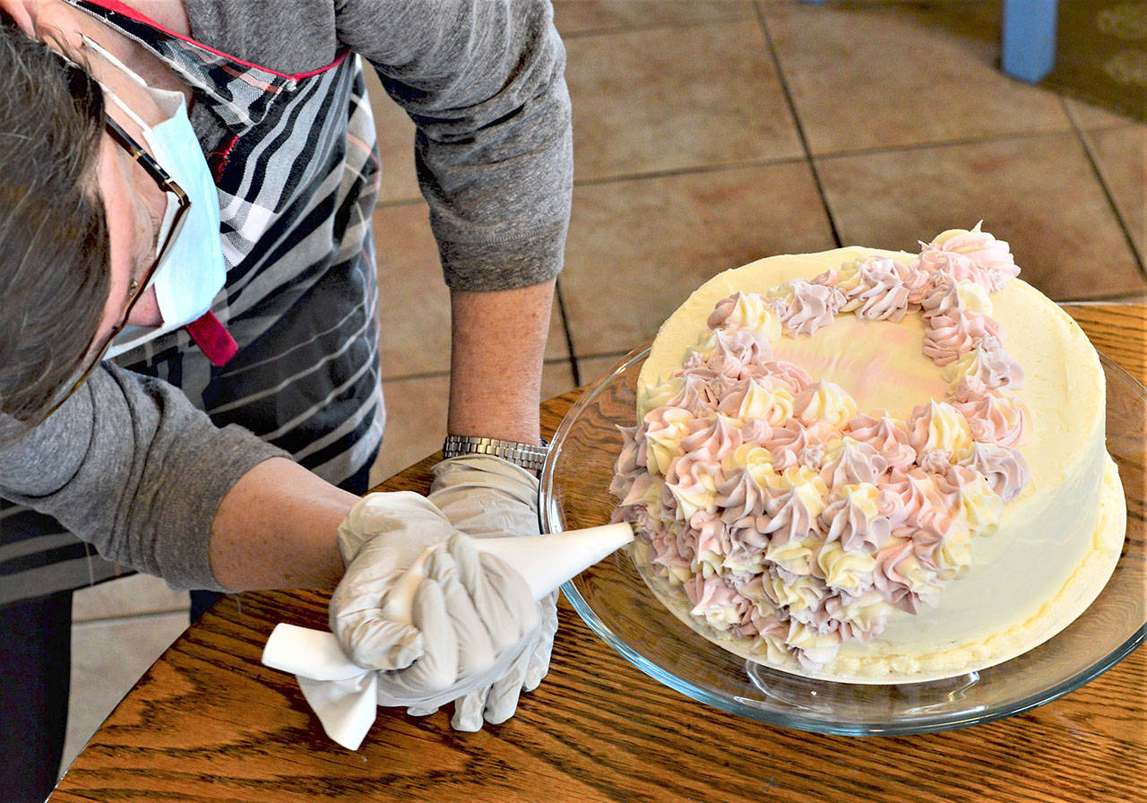 Volunteer Joan Coyne puts the icing on the cake for Jefferson County’s Cake4Kids project earlier this month. (Diane Urbani de la Paz/Peninsula Daily News)
