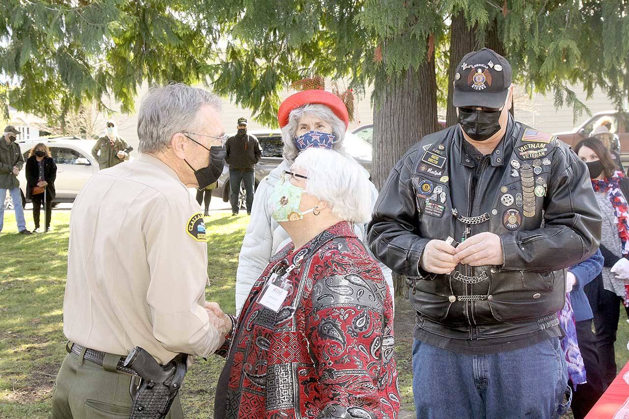 Joan Shields, center, the surviving spouse of Marvin Shields, is presented a commemorative certificate to honor her late husband’s heroic action during the Vietnam war, during which he was fatally wounded. Clallam County Sheriff Bill Benedict, left, presents Shields the award. Benedict, a Vietnam veteran, was presented a commemorative certificate in addition to serving as the keynote speaker. More than 25 Vietnam veterans were honored in the ceremony Monday at the Clallam County Veterans Center. (Dave Logan/For Peninsula Daily News)