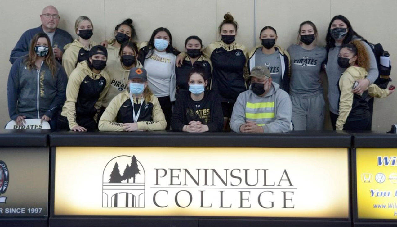 The Peninsula College women’s basketball team and coaching staff celebrated the letter of intent signing by Port Angeles senior Madison Cooke, seated center, Friday.