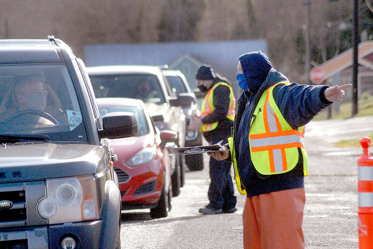 Keith Thorpe/Peninsula Daily News
Vaccination clinic workiers Jack Harmon, front, and Jeramey Johnson check in motorists and direct traffic during Saturday's clinic at Port Angeles High School.