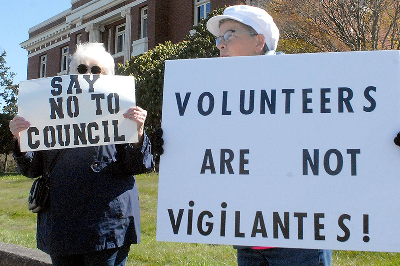 Keith Thorpe/Peninsula Daily News
Darlene Heskett, left, and Patty Pastore hold signs on Saturday in front of the Clallam County Courthouse in Port Angeles protesting what they said is inaction by the Port Angeles City Council in handling homelessness and drug abuse in the city, as well as having been termed "vigilantes" for their cleanup efforts. The pair were part of a group of about 15 people taking part in the protest.