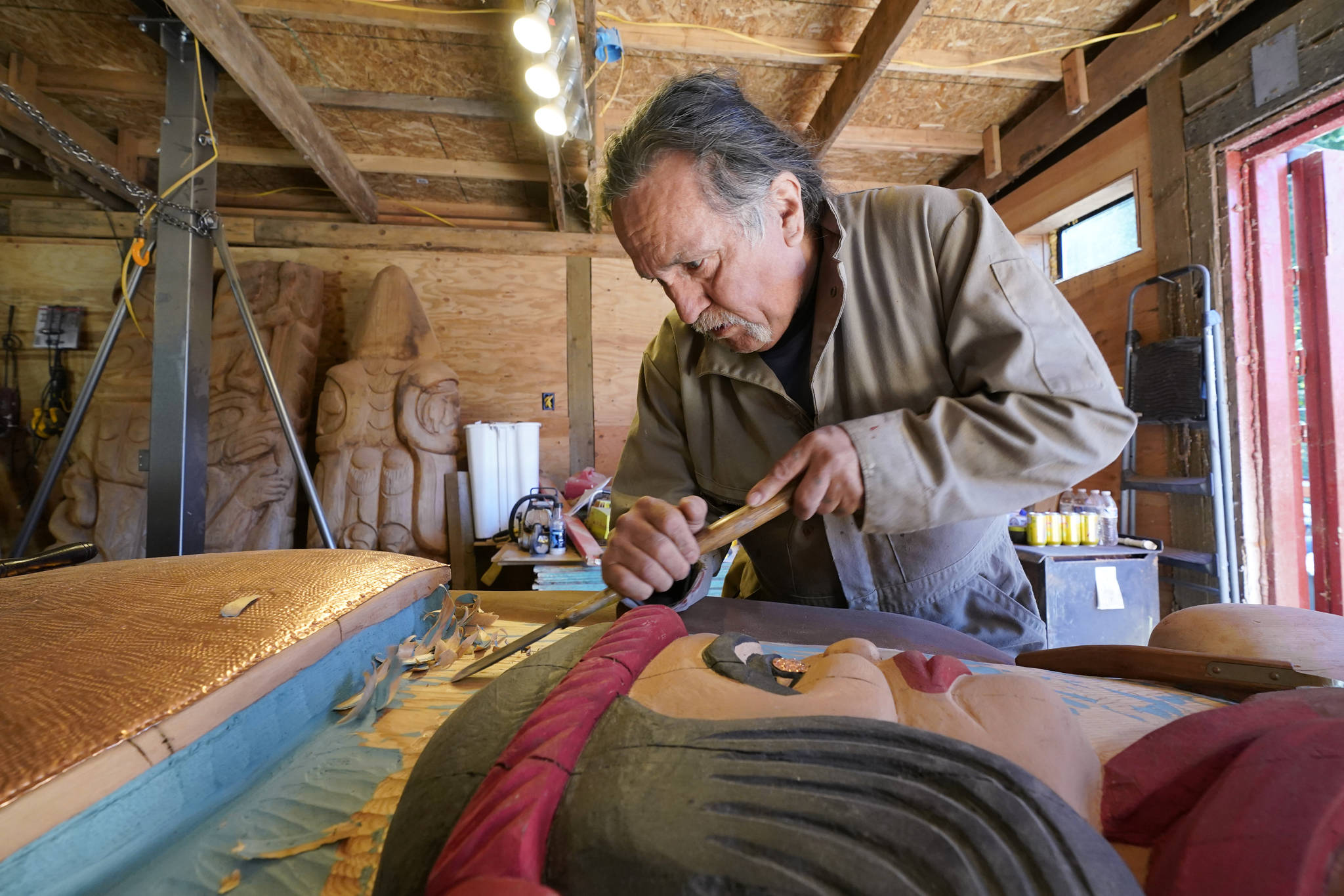 Lummi Nation lead carver Jewell James works on the final details on Monday of a nearly 25-foot totem pole to be gifted to the Biden administration from the Lummi Reservation near Bellingham. The pole, carved from a 400-year-old red cedar, will make a journey from the reservation past sacred indigenous sites before arriving in Washington, D.C., in early June. Organizers said the totem pole is a reminder to leaders to honor the rights of Indigenous people and their sacred sites. (Elaine Thompson/The Associated Press)