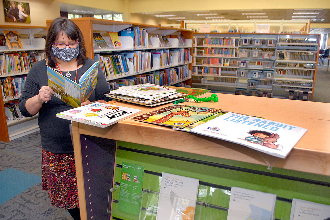 Jennifer Knight, youth services librarian at the Port Angeles Library, looks over a selection of books featured in Dolly Parton’s Imagination Library. (Keith Thorpe/Peninsula Daily News)