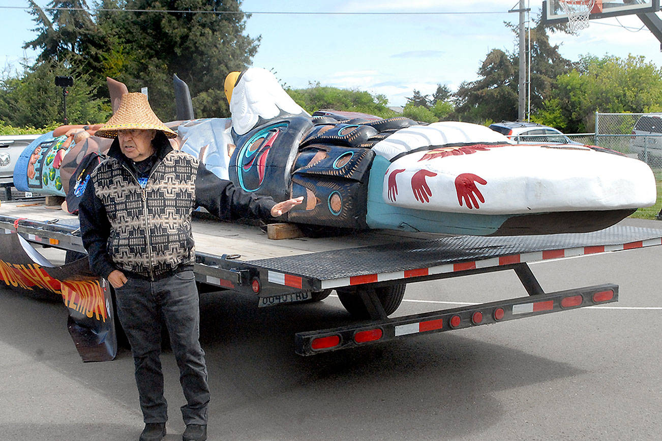 Lummi Nation totem carver Sit ki kadem, also called Doug James, explains the meaning of the elements of a totem that is traveling the United States on its way to Washington, D.C., during a stop on Tuesday at the Lower Elwha Reservation near Port Angeles. The journey, dubbed the Red Road to D.C., included a stop at the Olympic Unitarian Universalist Fellowship in Sequim on Tuesday. The 25-foot totem will be featured this fall at the Smithsonian National Museum of the American Indian. It is scheduled to return May 25 for an appearance at Port Angeles City Pier. (Keith Thorpe/Peninsula Daily News)