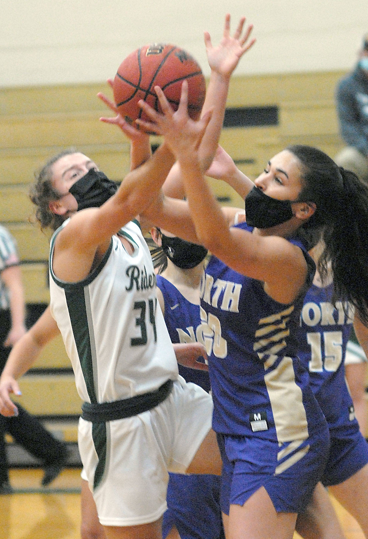Port Angeles’ Jaida Wood, left, and North Kitsap’s Mia McNair jostle for a rebound on Saturday evening at Port Angeles High School. (Keith Thorpe/Peninsula Daily News)