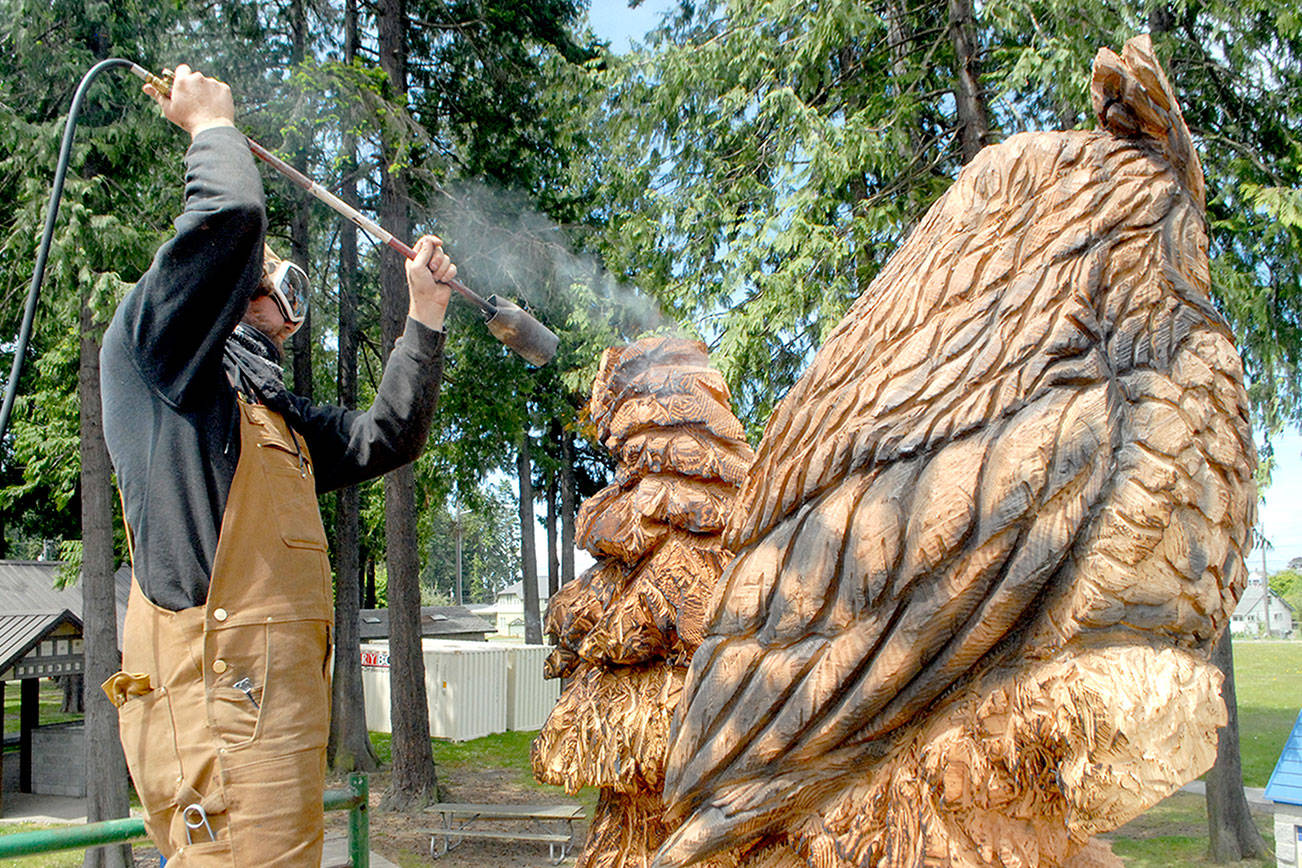 Keith Thorpe/Peninsula Daily News
Carver Jeff Eshom uses a gas torch on Thursday to burn sections of a wood sculpture his is creating at the site of the new Dream Playground at Erickson Playfield in Port Angeles.