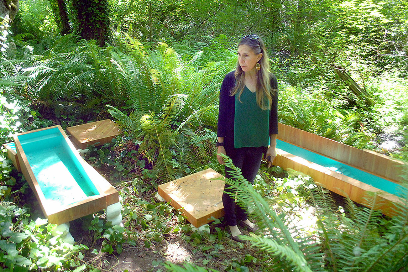 Port Angeles Fine Arts Center executive director Christine Loewe admires an art installation, “The Pool Zone” by Chris Oliver, debuting Saturday in the Webster’s Woods Sculpture Park. (Keith Thorpe/Peninsula Daily News)