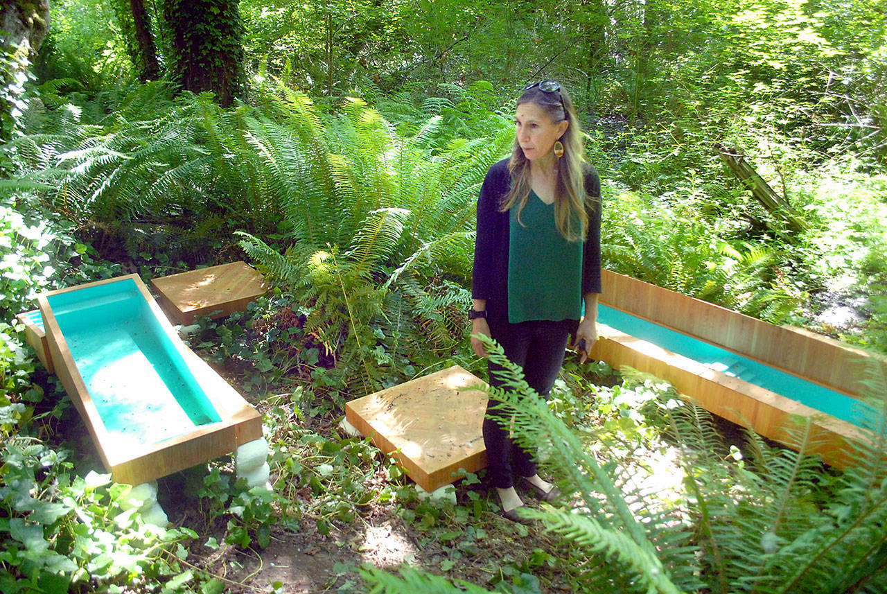 Port Angeles Fine Arts Center executive director Christine Loewe admires an art installation, “The Pool Zone” by Chris Oliver, debuting Saturday in the Webster’s Woods Sculpture Park. (Keith Thorpe/Peninsula Daily News)
