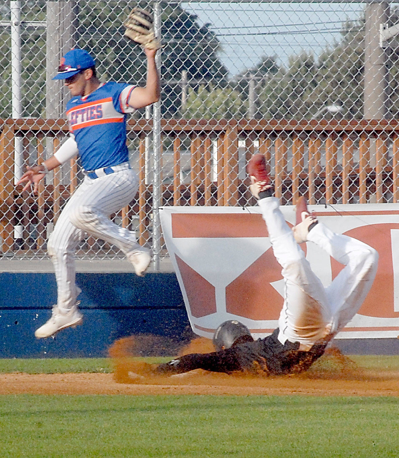 Keith Thorpe/Peninsula Daily News Lefties third baseman Ricardo Amavizca leaps up for the ball as Driveline’s Thomas Rudinsky slides into base during the third inning on Friday night at Port Angeles Civic Field.