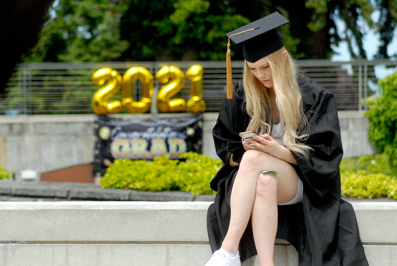 Peninsula College graduate Mackenzie Jay of Sequim looks at her cellphone in Pirate Square prior to the beginning of Saturday’s ceremony to award associate of arts degrees on the Port Angeles campus. A total of 413 students were qualified to receive degrees and certificates as part of the Class of 2020 and 2021. (Keith Thorpe/Peninsula Daily News)