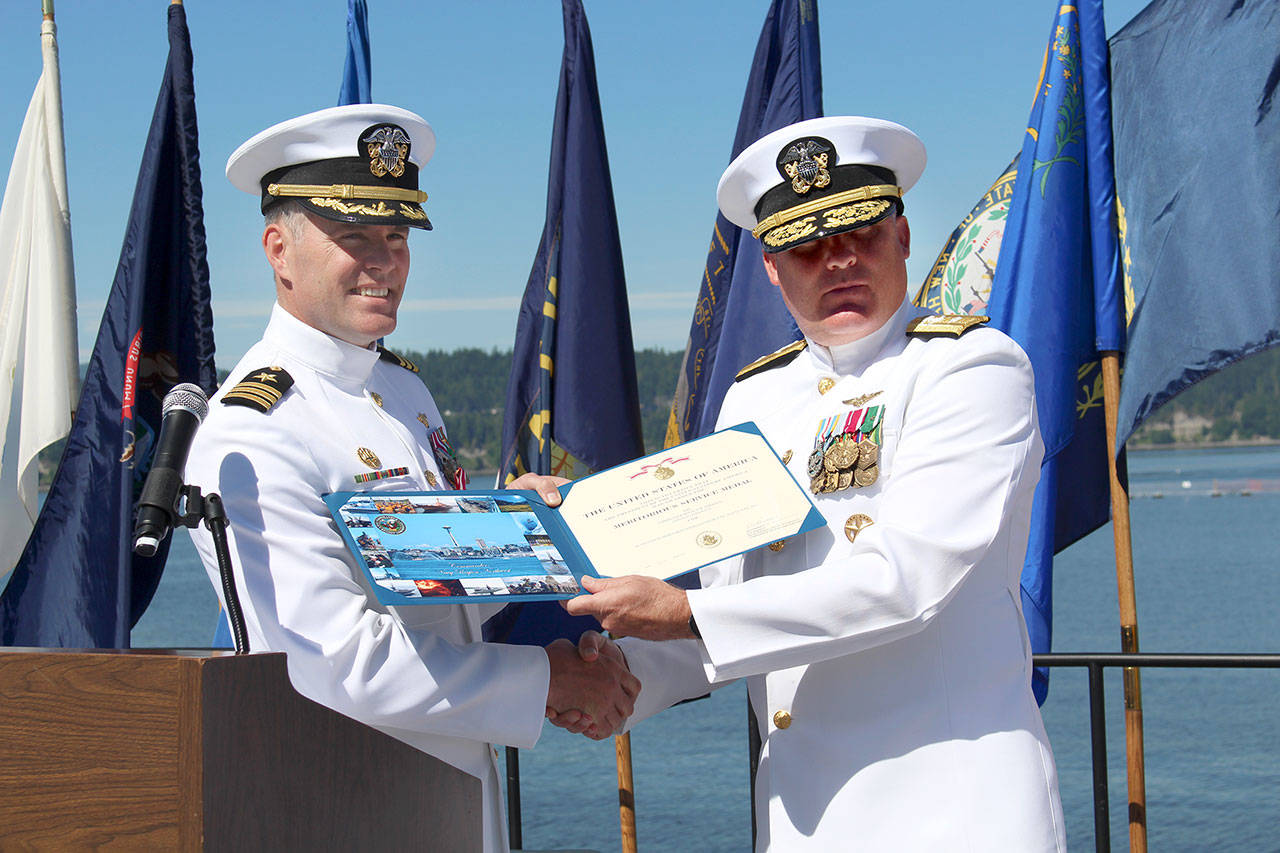 Commander Donald Emmerson, left, receives the Meritorious Service Medal from Rear Admiral Brad Collins, commander of Navy Region Northwest, during Naval Magazine Indian Island’s Change of Command ceremony on Thursday. Emmerson’s role of commanding officer is now filled by Commander Andrew Crouse. (Zach Jablonski/Peninsula Daily News)